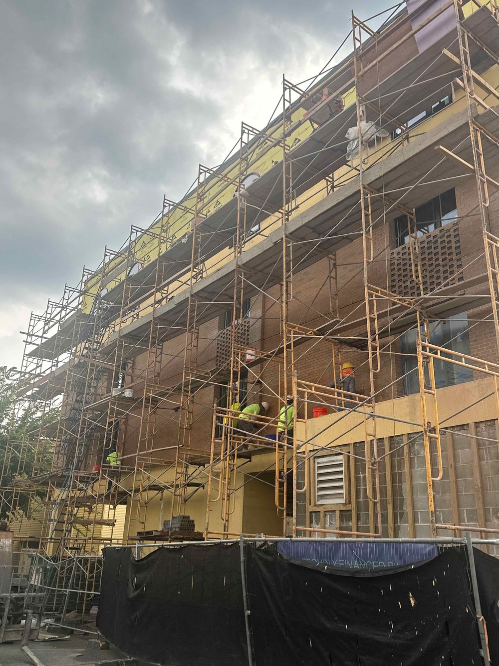 Multi-storey building under construction, wood framing behind scaffolding